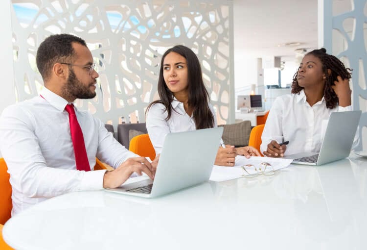 Group of business people talking during meeting. Handsome young businessman typing on laptop. Business meeting concept