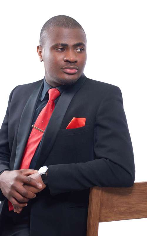 Portrait of african business man seriously posing and looking away, leaning on chair and holding hands together. Confident male wearing elegant black suite and red tie. Isolate on white background.
