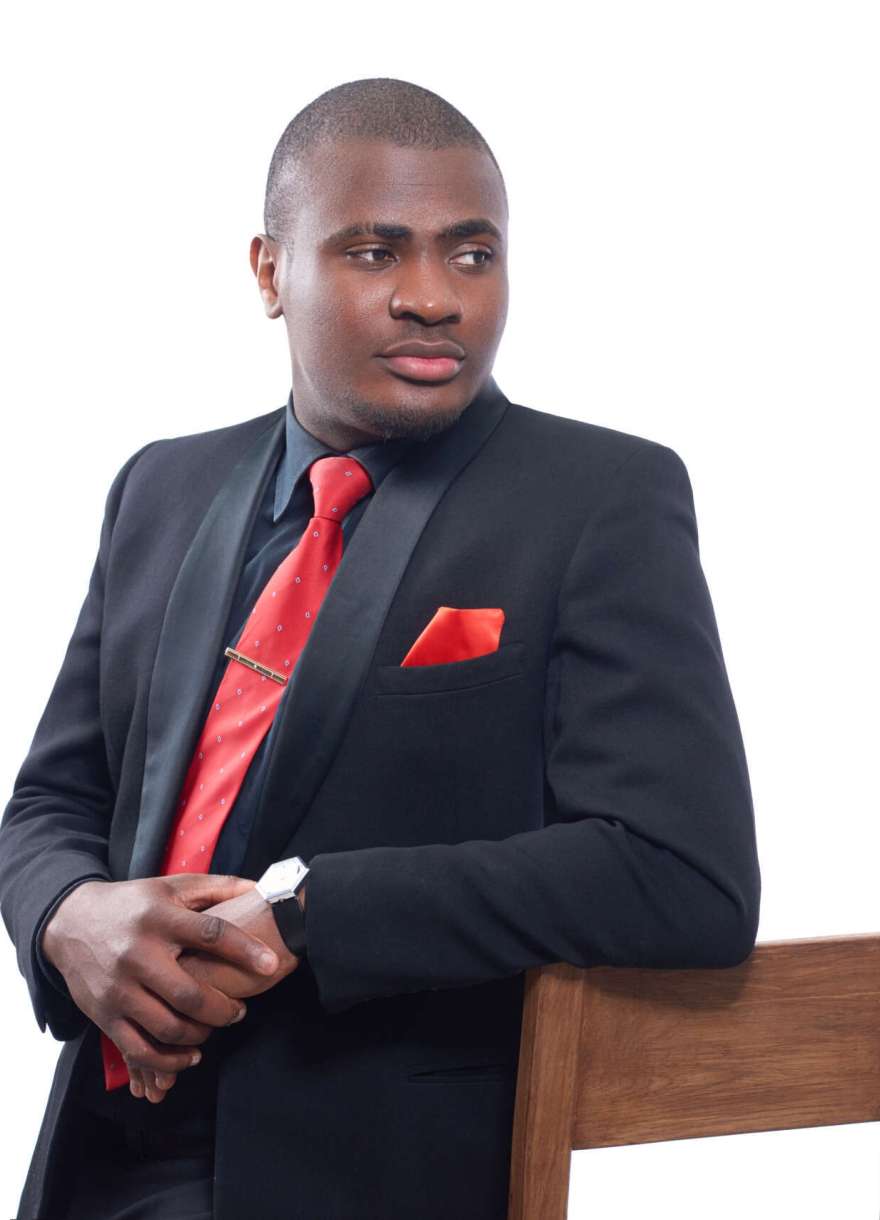 Portrait of african business man seriously posing and looking away, leaning on chair and holding hands together. Confident male wearing elegant black suite and red tie. Isolate on white background.