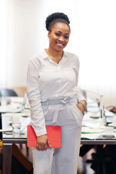 Face of handsome african american business woman, holding tablet on the background of business peoples multiracial team meeting, sitting in office table.